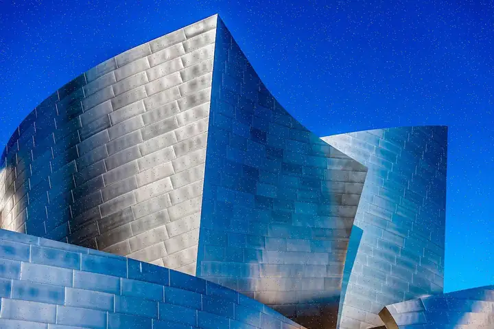 The curved metallic façade of a modern concert hall under a blue sky