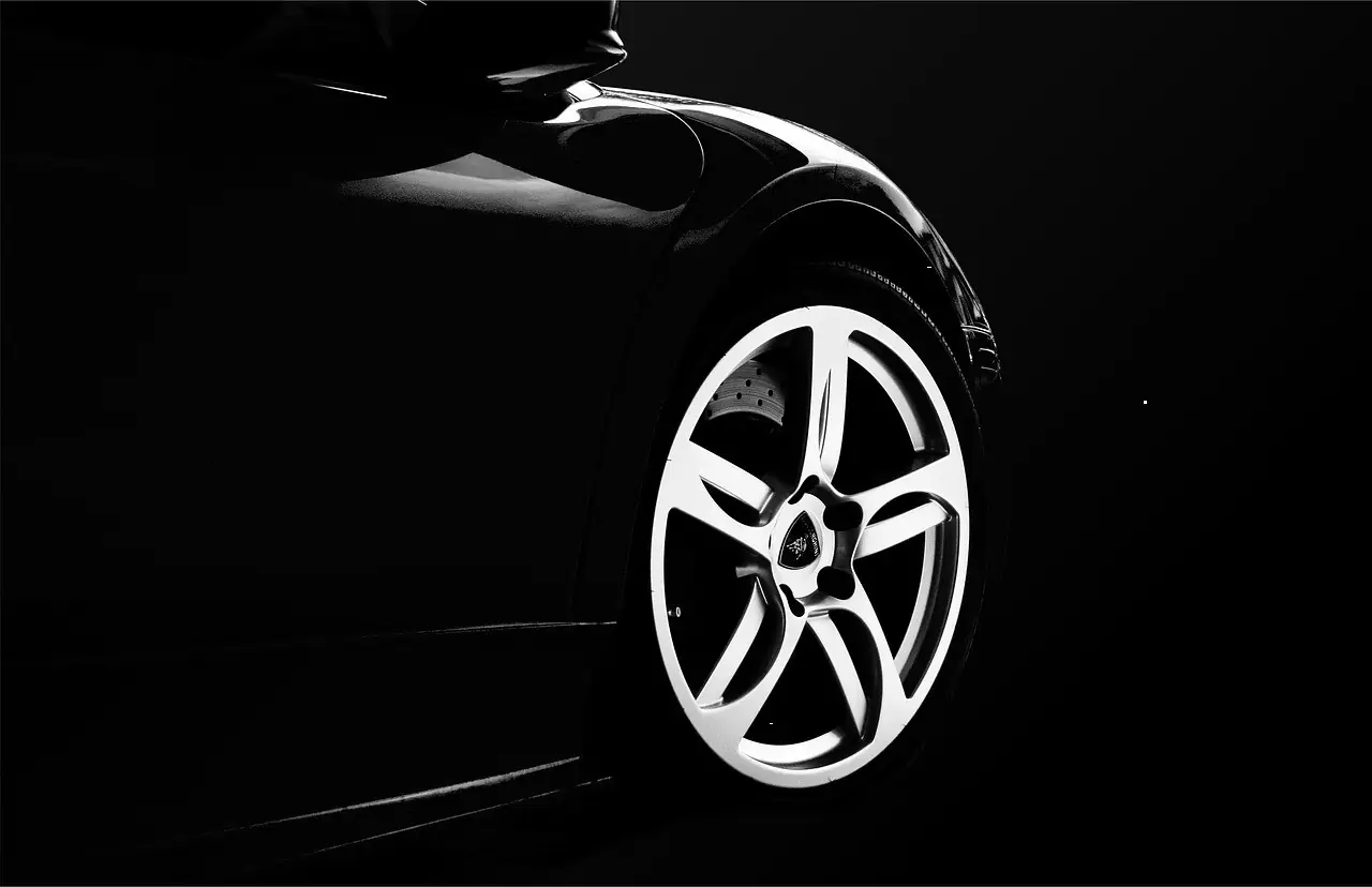The alloy wheel of a black sports car against a black background